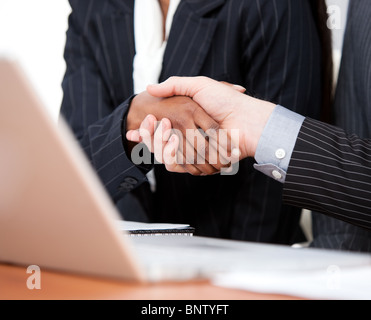 Close-up of a handshake between two businessmen with laptop Stock Photo