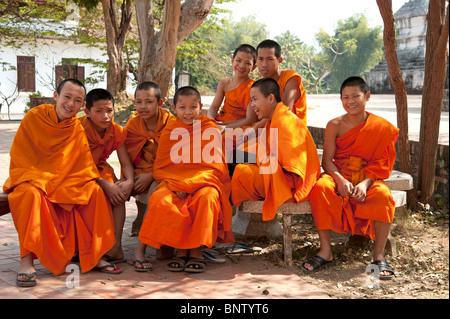 Novice Buddhist monks sitting in the grounds of a temple in Luang Prabang Laos Stock Photo