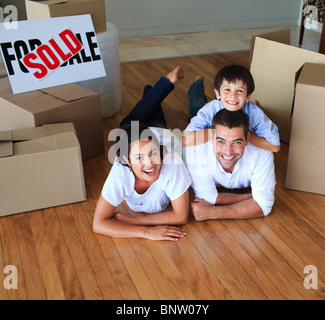Family moving house on floor smiling at the camera Stock Photo