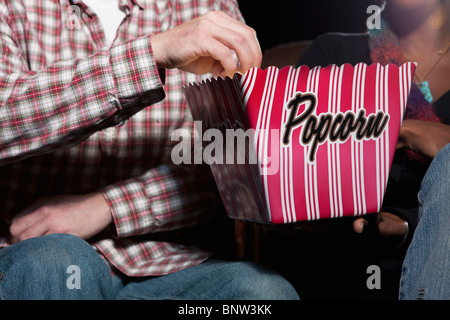 Couple eating popcorn in movie theatre Stock Photo