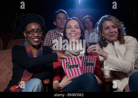 Three woman sharing popcorn in movie theatre Stock Photo