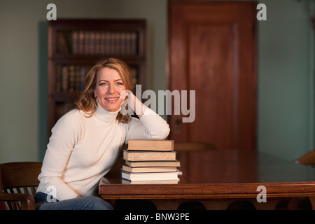 Woman leaning on stack of books Stock Photo