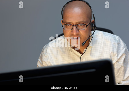 Man wearing headset working on computer Stock Photo