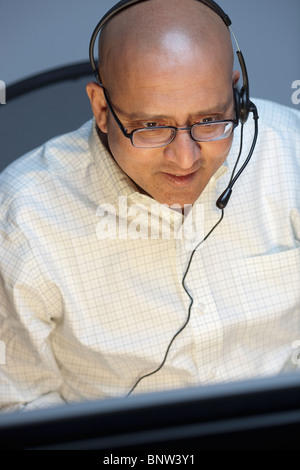 Man wearing headset working on computer Stock Photo