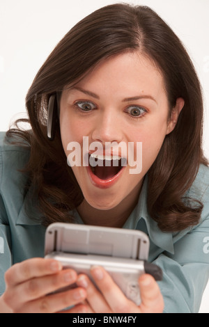 Surprised woman looking at hand held device Stock Photo