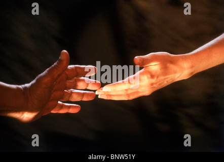 Afro American male hand reaching for Caucasian female hand Stock Photo