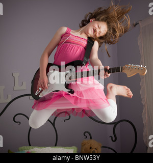 Young girls playing guitar on her bed Stock Photo
