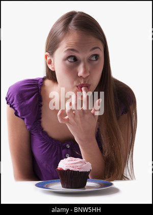 Woman sneaking a lick of icing from a cupcake Stock Photo