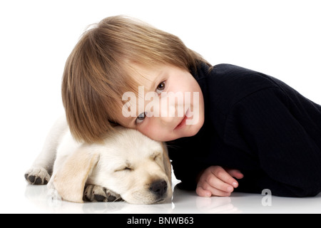 Child lying with head on sleeping Labrador retriever puppy Stock Photo