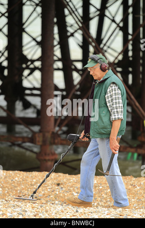 A man searches for buried treasure using a metal detector on Eastbourne Beach, East Sussex, England Stock Photo