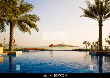 The infinity swimming pool in one of the beach clubs on the Palm Island Jumeira in Dubai. Burj al Arab visible in the distance. Stock Photo