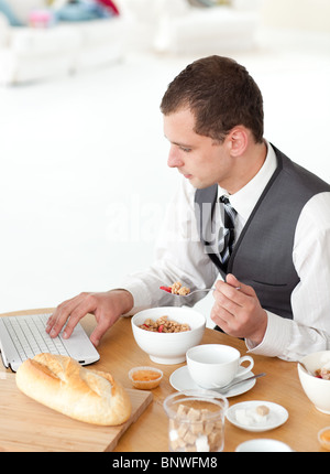 Young businessman using a laptop while having breakfast Stock Photo