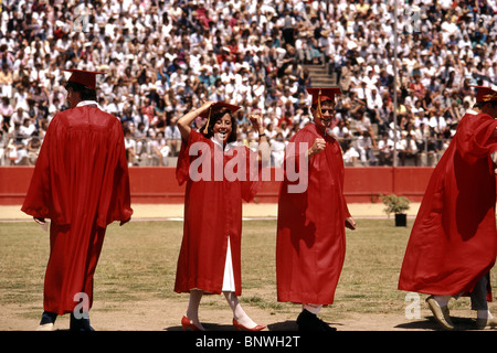 Triumphant high school seniors in red caps and gowns march at their graduation ceremony in Mission Viejo, California. Stock Photo