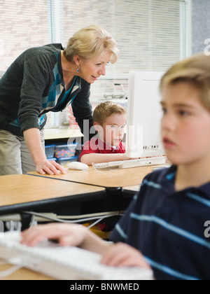 Teacher helping young student in computer lab Stock Photo