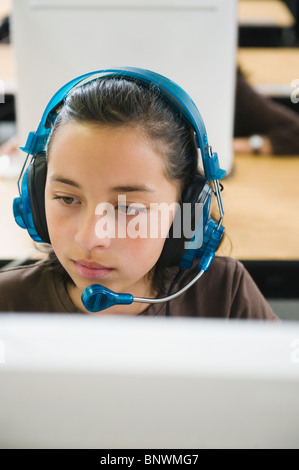 Focused biracial girl wearing headphones and learning at home using ...