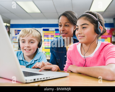 Teacher helping students use laptop Stock Photo