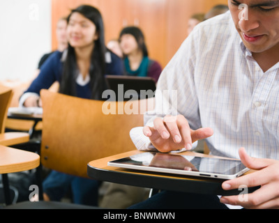 College students taking notes in lecture hall Stock Photo