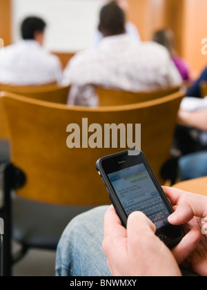 College student texting in lecture hall Stock Photo