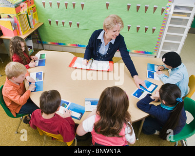 Kindergarten students sitting at table with their teacher Stock Photo