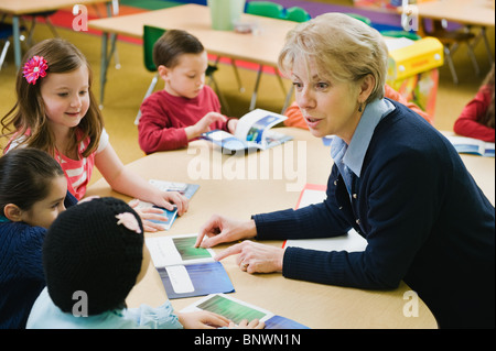 Kindergarten students sitting at table with teacher Stock Photo