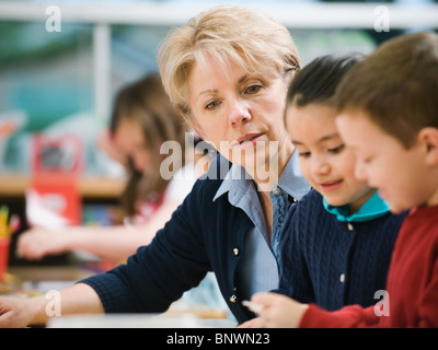 Teacher sitting at table with kindergarten students Stock Photo
