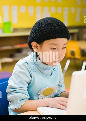 Kindergarten student working on laptop in classroom Stock Photo