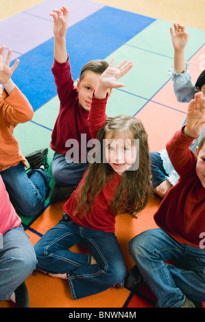 Elementary school students raising their hands Stock Photo