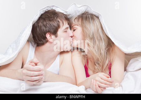 Couple kissing under the covers Stock Photo