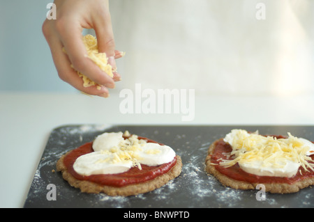 grated cheddar cheese on wholemeal mini pizzas Stock Photo