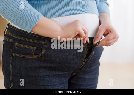 Overweight woman buttoning up her jeans Stock Photo