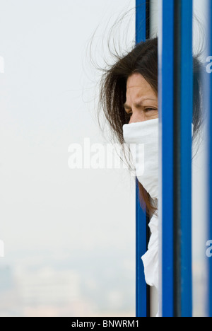 Muscovite woman in protective mask looking from a window Stock Photo
