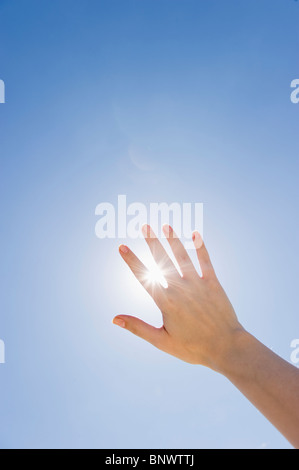 Hand held up in front of sunshine