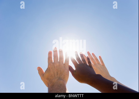 Hands held up in front of sunshine Stock Photo