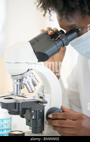 Researcher looking at specimen through microscope Stock Photo
