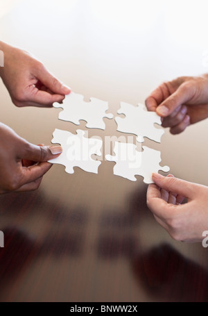 Four hands holding puzzle pieces Stock Photo