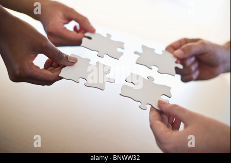 Four hands holding puzzle pieces Stock Photo