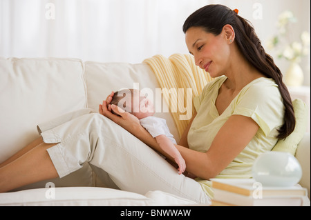 Mother sitting on couch with her baby Stock Photo