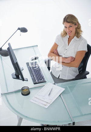 Confident businesswoman sitting at modern desk Stock Photo