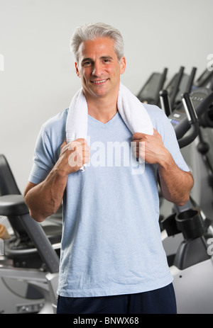 Man at the gym standing with towel around his neck Stock Photo