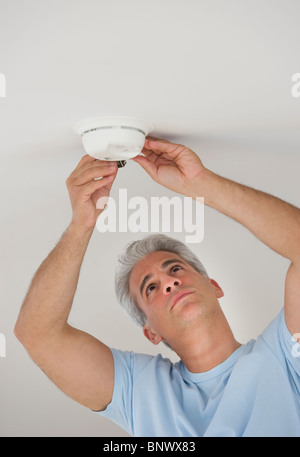 Man changing battery in smoke detector Stock Photo