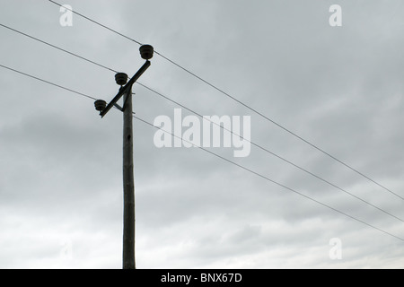 Three phase electrical power cables against a backdrop of grey sky, Ardnamurchan, Scotland Stock Photo
