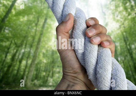 man hand grab grip strong climbing to green forest tree big rope Stock Photo