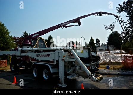 Concrete pumper truck uses extra long hydraulic boom arm hose pipe to reach foundation forms at house construction site Stock Photo