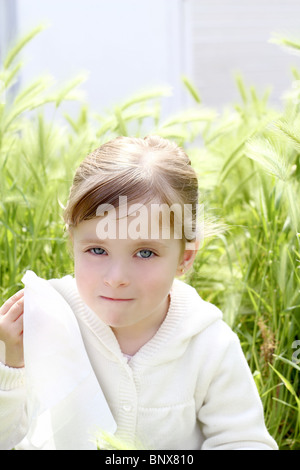 sad little girl crying outdoor green meadow field cereal spike grass Stock Photo