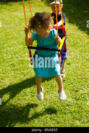 Baby brunette girl on the swing - seesaw and boy Stock Photo