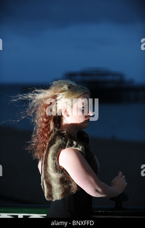 Blonde hair model with avant garde style fashion black dress on Brighton seafront near the West Pier UK Stock Photo