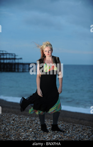 Blonde hair model with avant garde style fashion black dress on Brighton seafront near the West Pier UK Stock Photo