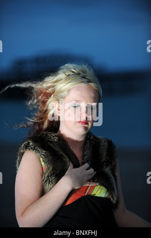 Blonde hair model with avant garde style fashion black dress on Brighton seafront near the West Pier UK Stock Photo