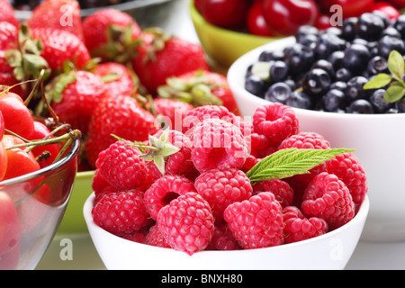 Different berries in bowls. Bowl with tempting raspberries in a front.