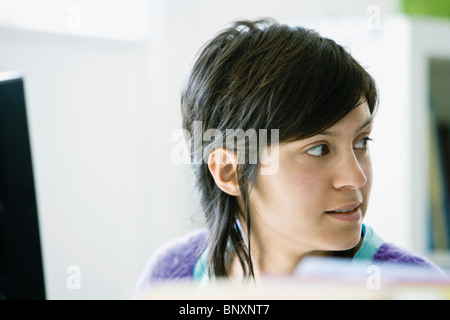 Young woman in office distracted from work Stock Photo